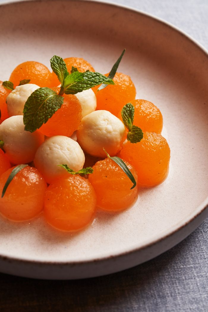About Elegant dessert arrangement with melon and cheese balls garnished with fresh mint leaves.